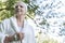 Smiling sick elderly woman in dressing gown in the forest