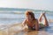 Smiling slender lady in a swimsuit is sunbathing in shallow water washed by a sea wave