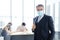 Smiling and Smart Caucasian businessman in black suit and asian staff and teamwork wearing masks prevent covid 19 virus at office