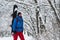 Smiling snowboarder with backpack walks through the forest