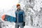 Smiling snowboarder holding board for snowboarding