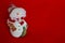 Smiling snowman statuette on red background as winter holidays concept.