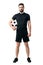 Smiling soccer or futsal player wearing black sportswear holding ball under his arm looking at camera