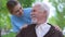 Smiling social worker taking care of aged pensioner, nursing home volunteering