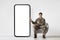 Smiling soldier in military uniform sitting by huge phone, mockup