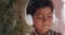 Smiling South Asian child listening to music with headphones