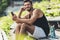 smiling sportsman with bottle of water listening music with smartphone and earphones on bench