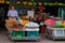 Smiling street fruit seller, baskets with tropical fruits, street trading in Southeast Asia