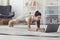 Smiling strong millennial girl making plank in front of laptop in living room online.