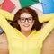 Smiling student in eyeglasses lying on floor