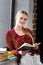 Smiling student in glasses holding book in apartment