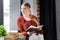 Smiling student in glasses holding book in apartment