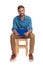 Smiling student sits on wooden chair and holdis clipboard