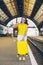smiling stunning woman with yellow suitcase on wheels at railway station
