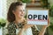 Smiling stylish small business owner woman showing open sign