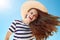 Smiling stylish woman with fluttering hair against blue sky