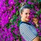 Smiling stylish woman near colorful magenta flowers bed