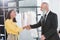 Smiling stylist greeting grey haired customer indoors