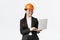 Smiling successful female asian industrial engineer, factory manager in safety helmet and business suit using laptop