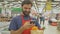 Smiling supermarket employee using mobile phone and holding shopping bag in supermarket