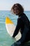 Smiling surfer sitting on surfboard at seacoast