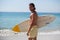 Smiling surfer with surfboard standing at beach coast