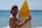 Smiling surfer with surfboard standing at beach coast