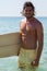 Smiling surfer with surfboard standing at beach coast