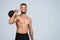 Smiling sweat strong muscular millennial european guy with beard, naked torso make exercises with kettlebell