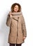 Smiling tall woman poses showing modern stylish beige sheepskin coat combined with textile sleeves and knitted scarf