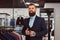 Smiling tattoed male with stylish beard and hair dressed in elegant suit standing in menswear store.