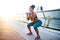 Smiling tattooed woman doing sit ups with barbells in arms