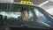 Smiling taxi driver sitting in a car and driving around the city. Slow motion