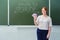 Smiling teacher holds money in euro bills standing on a background of green blackboard. Text