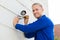 Smiling Technician Installing Camera On Wall