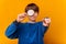 Smiling teen boy is looking through a magnifying glass and pointing at you.