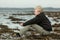 Smiling teen boy sitting on beach during low tide