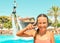 Smiling teen girl enjoing summer vacation at the pool with fly board watershow on the background