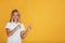 Smiling teen pretty blonde girl pupil in white t-shirt pointing her fingers at empty space