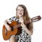 Smiling teenage girl in dress plays the guitar in studio
