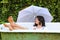 Smiling teenage girl lying in bathtub with umbrella