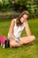 Smiling teenage girl sitting grass with satchel