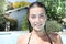 Smiling teenage girl sitting in pool near home