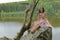 Smiling teenage girl sitting on rock above river