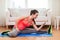 Smiling teenage girl streching on floor at home