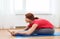 Smiling teenage girl streching on floor at home