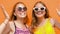 Smiling teenage girls in sunglasses waving hands