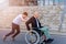 Smiling teenage son with disabled handsome father on wheelchair on a walk.