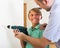 Smiling teenager assist father to using drill