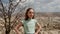 Smiling thoughtful teenage girl looking away while standing against mountain